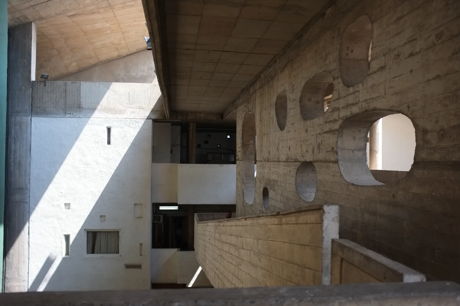 Haute Cour de Chandigarh : un vaste portique de béton abrite la façade, devant trois piles peintes en vert, rouge et jaune.