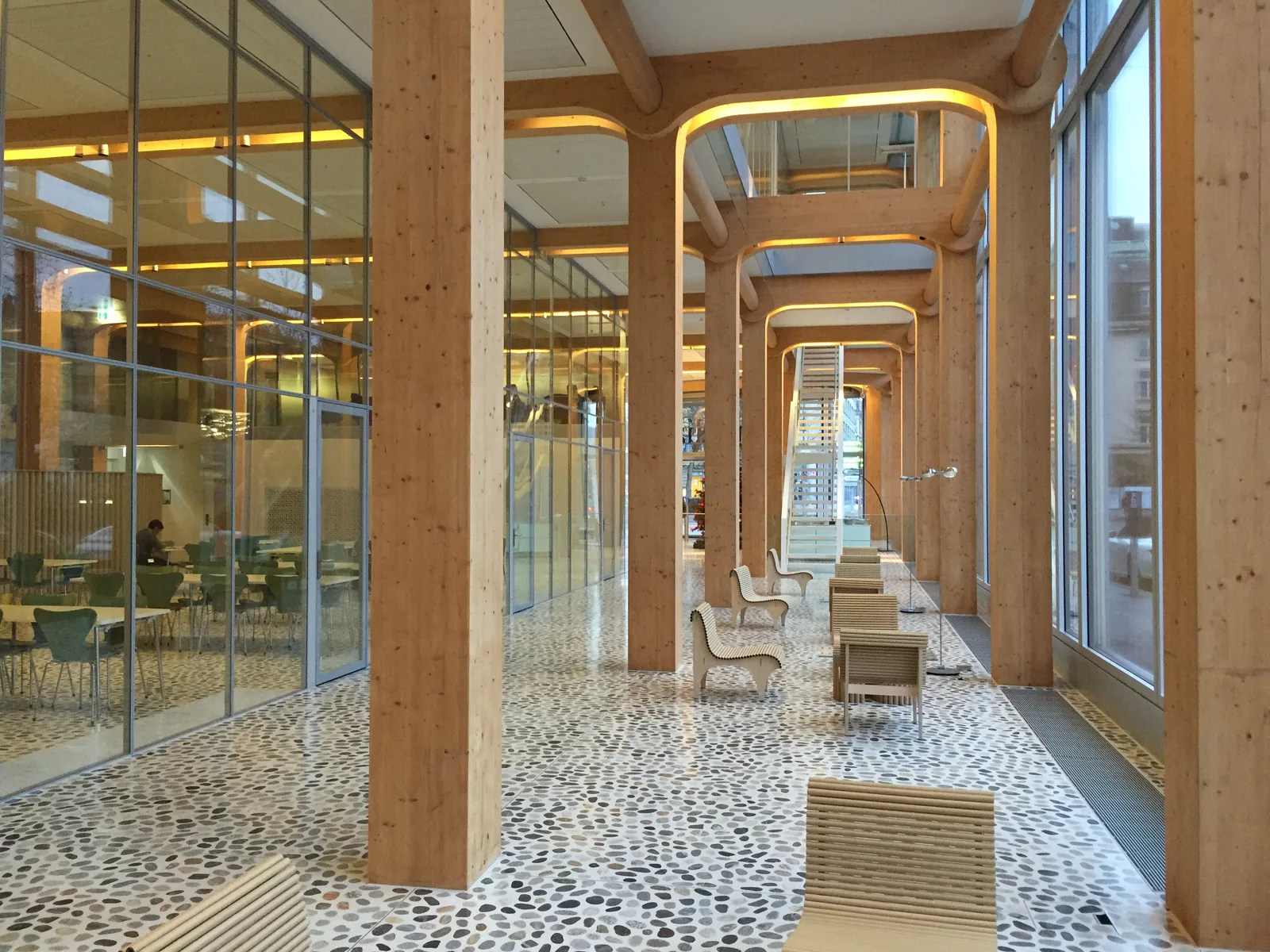 L'atrium intérieur de l'immeuble Tamedia à Zurich, de Shigeru Ban : poteaux ronds et poutres courbes en bois lamellé-collé apparent, baignés de lumière.