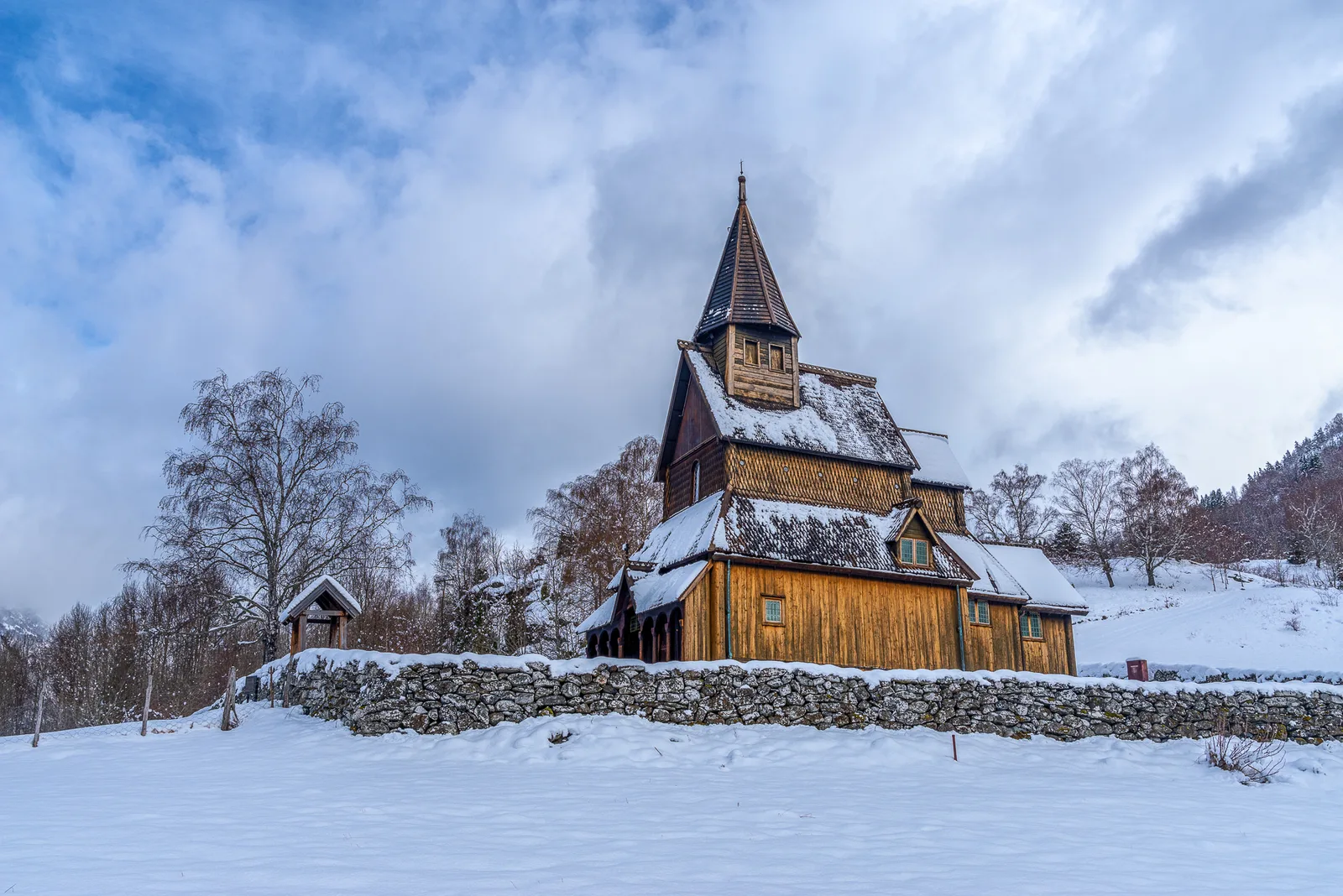 L'église en bois debout d'Urnes, en Norvège, aux parois et à la toiture de bois sombre, sous un ciel clair.